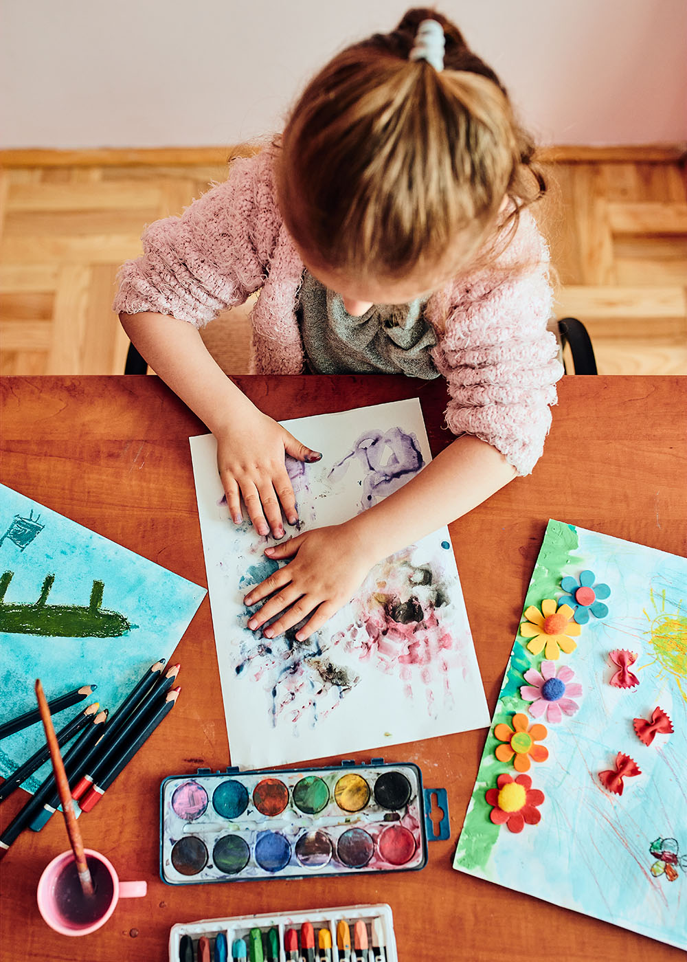 Overhead view of little girl finger painting and crafting