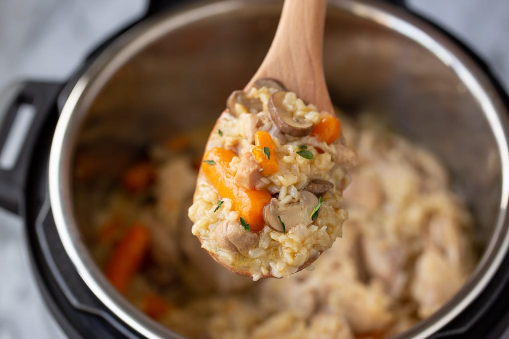 instant pot chicken and brown rice with carrots, rice and chicken on a spoon over the instant pot