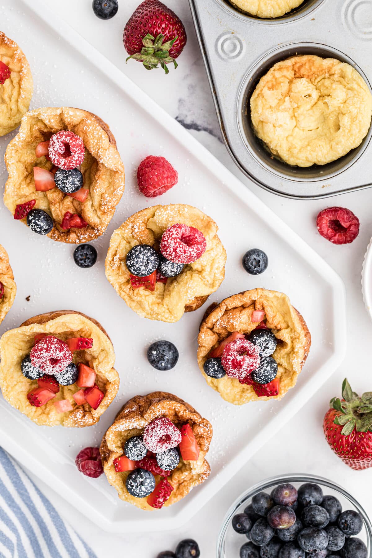 overhead view of popovers with berries and powdered sugar