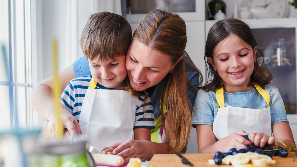 Mom helping two kids in kitchen