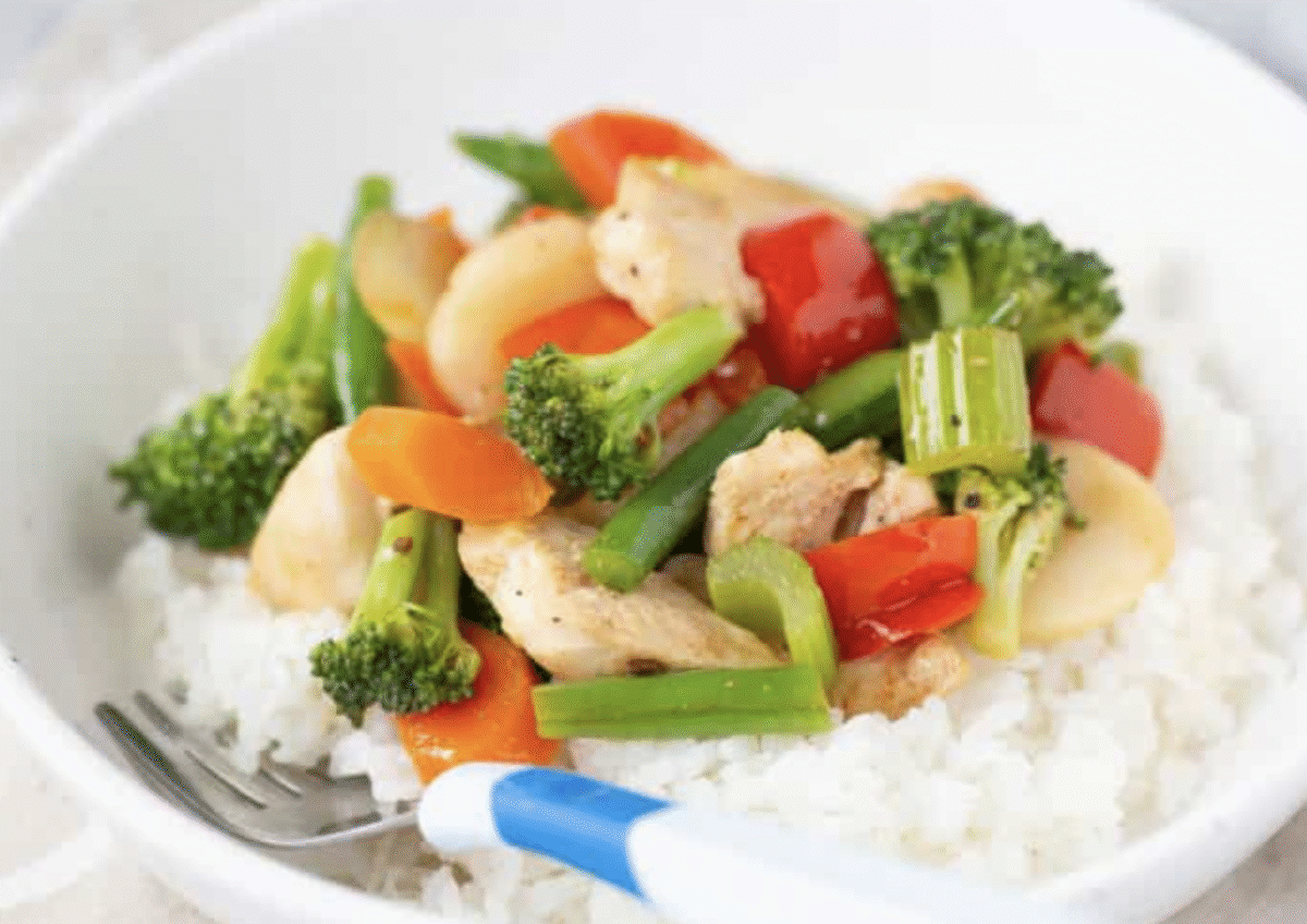 Chicken and veggie stir fry on white rice with a fork.