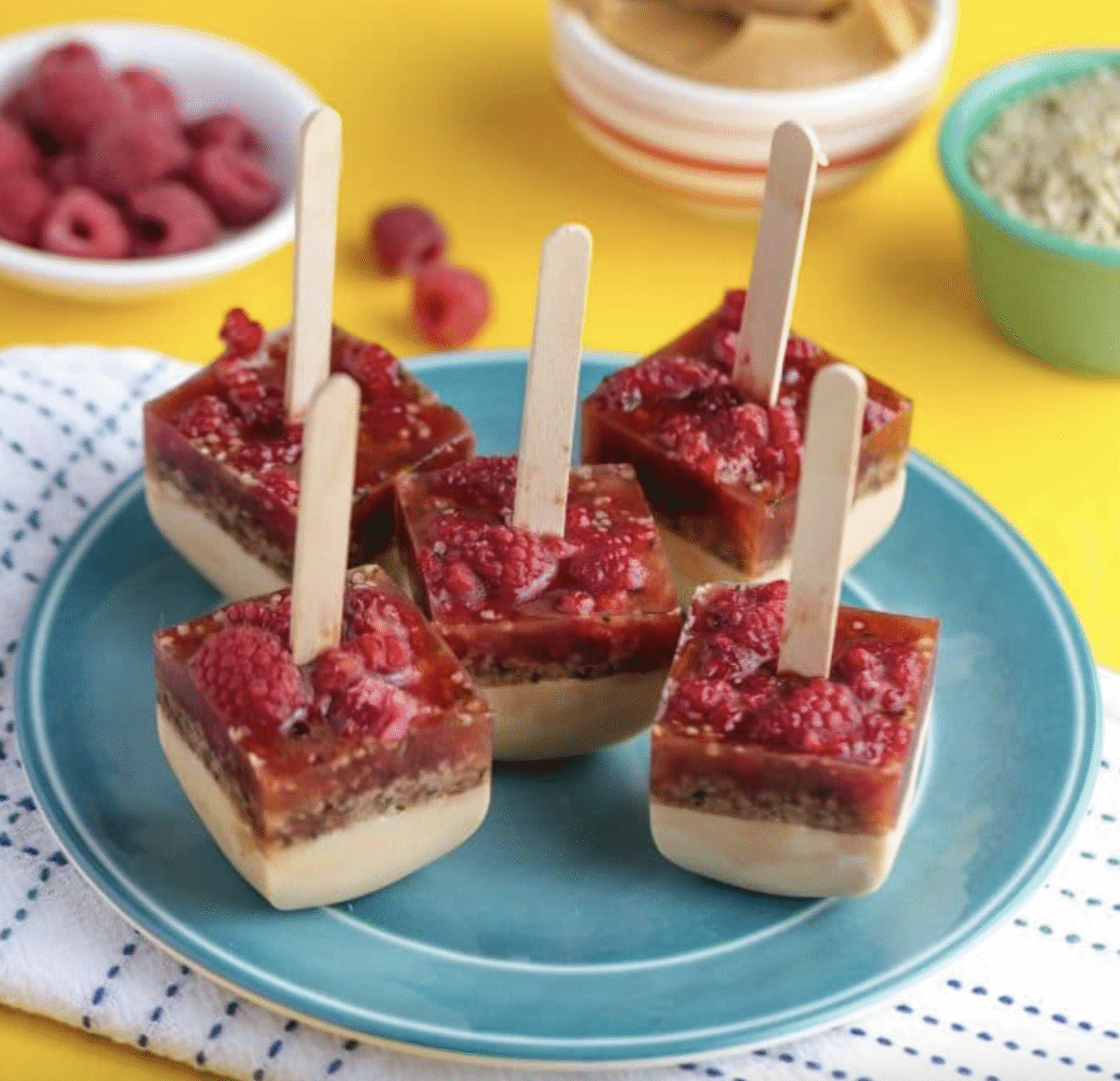 Peanut butter and berry pops on popsicle sticks placed on a blue serving plate.