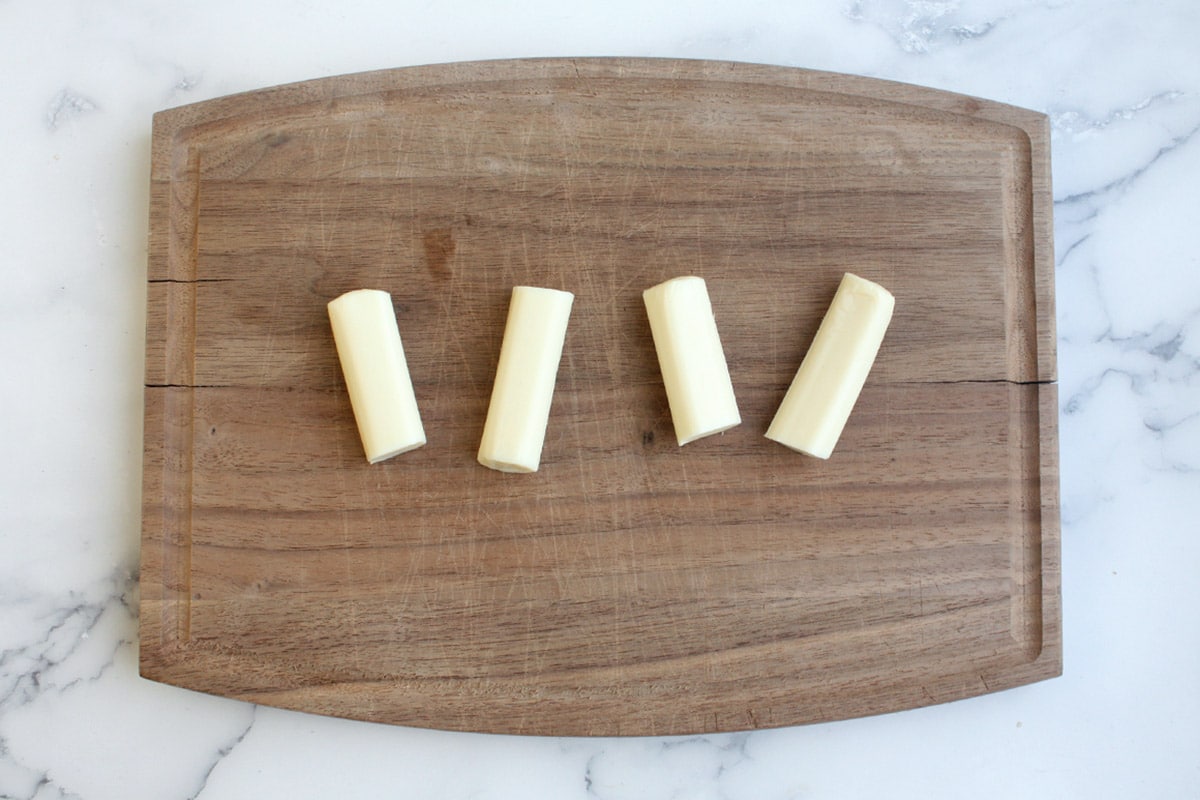 string cheese cut in half on a wooden cutting board