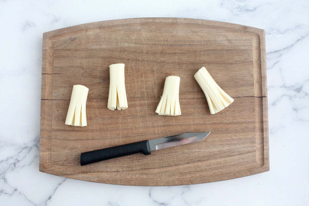 string cheese cut with a knife to resemble the bottom of a broom