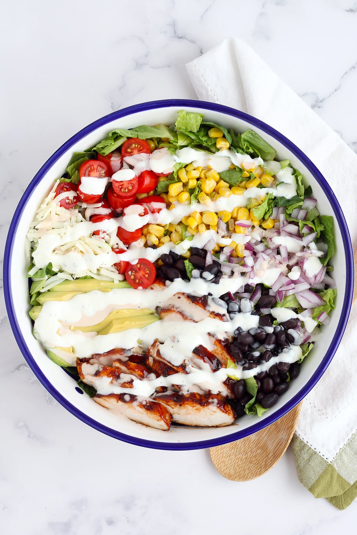 A refreshing bbq chicken salad topped with fresh vegetables, chicken, and mozzarella cheese drizzled with ranch dressing. 