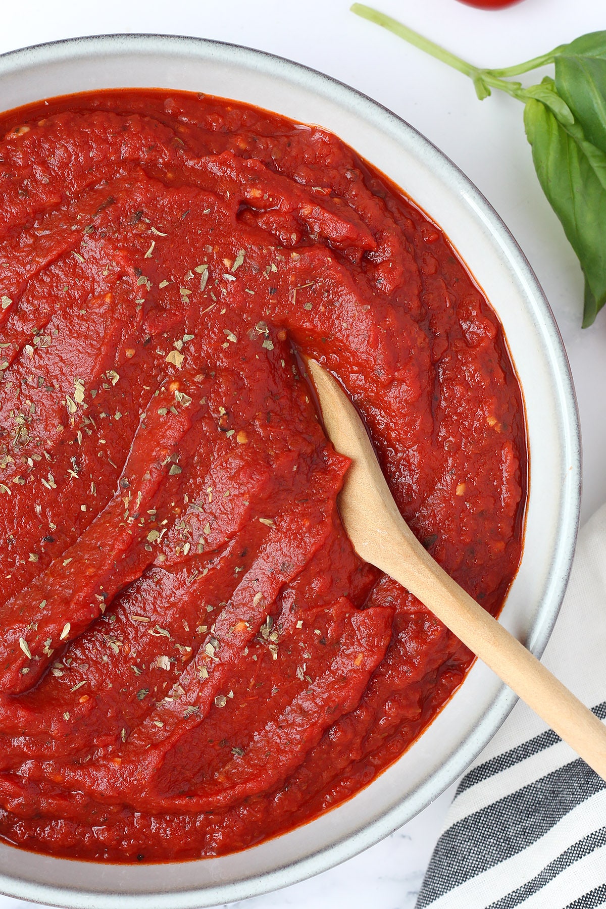 A bowl of thick homemade pizza sauce with a wooden spoon. 