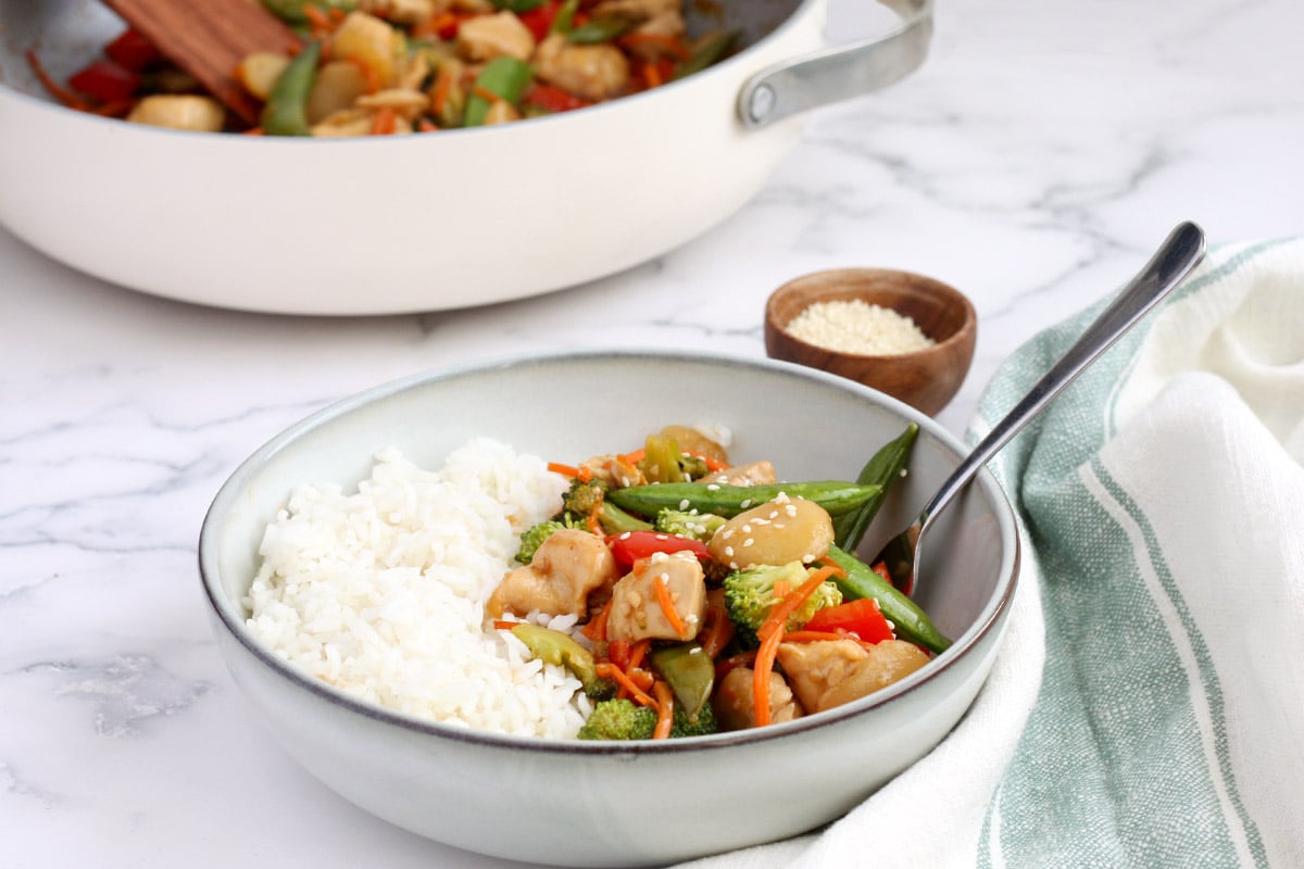 bowl of chicken stir fry with a green striped towel