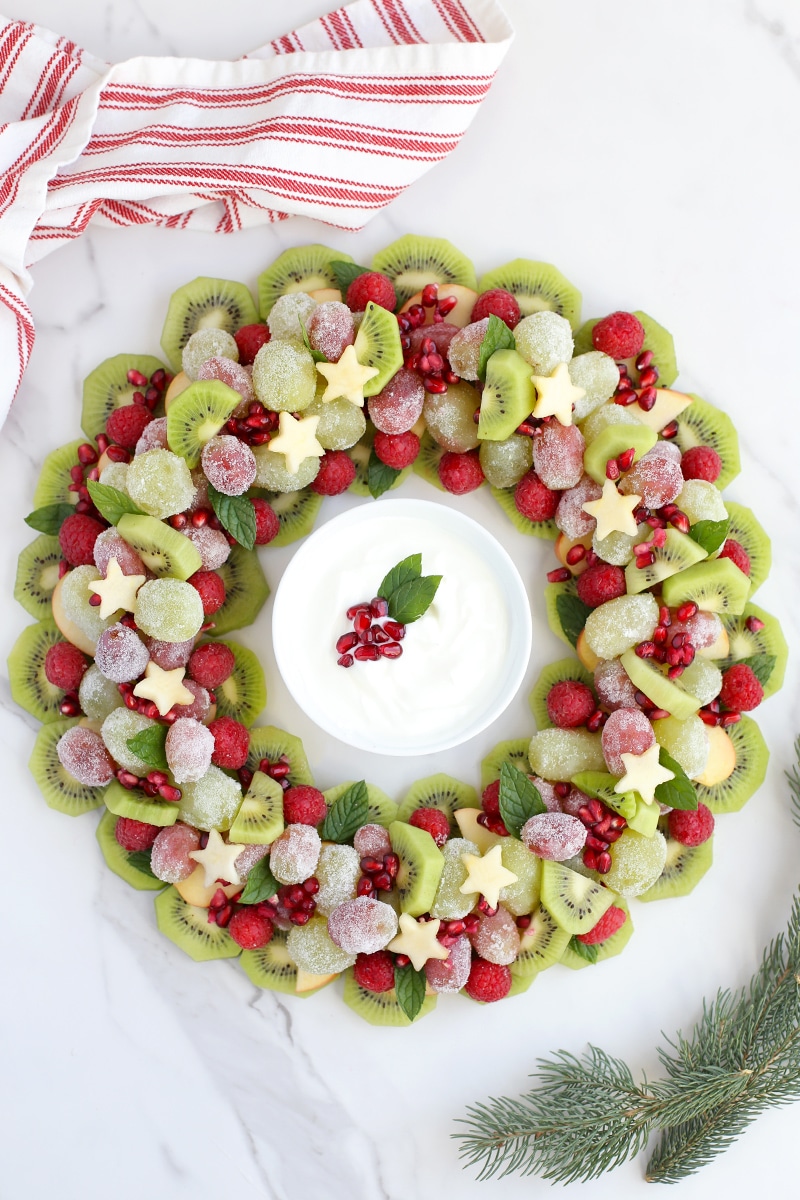 A Christmas fruit tray made with grapes, kiwi and apples shaped into a wreath. 