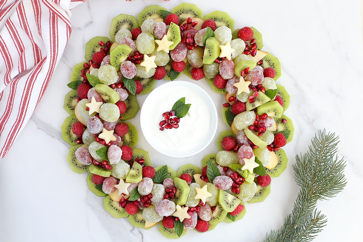 A Christmas Fruit Tray with sugared grapes and pomegranate with a yogurt fruit dip. 