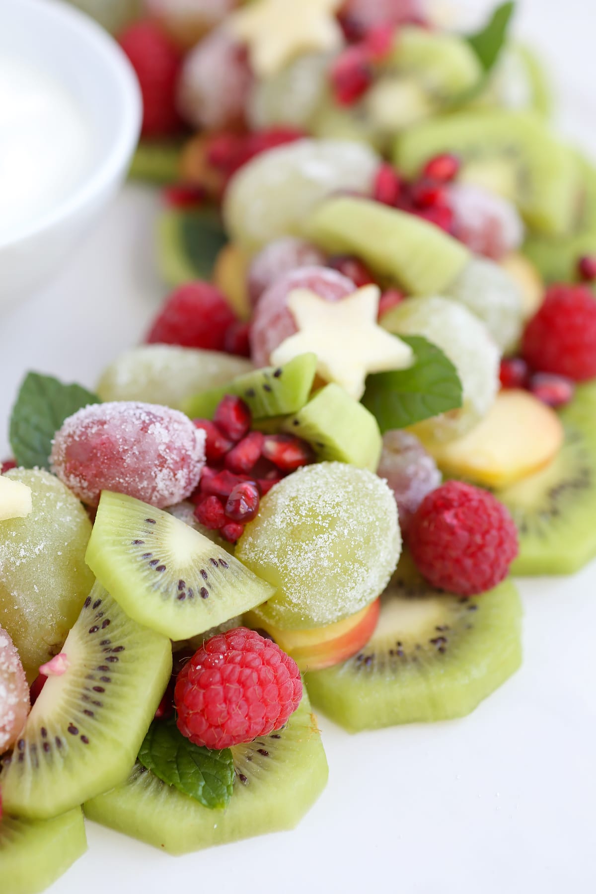 A close up image of winter fruits shaped into a wreath and topped with apple stars. 