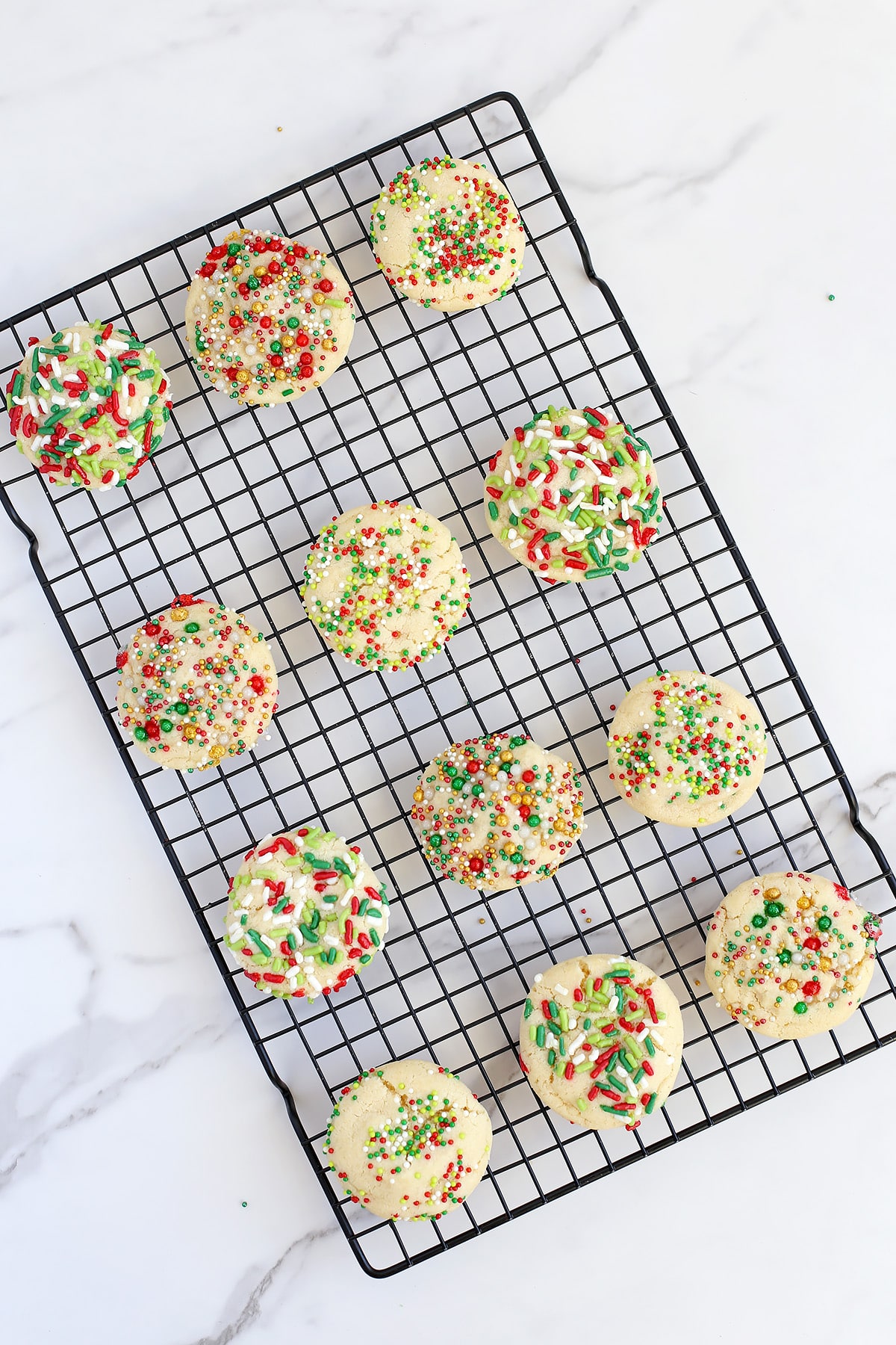 Christmas sugar cookies lined up on a wire cooling rack. 