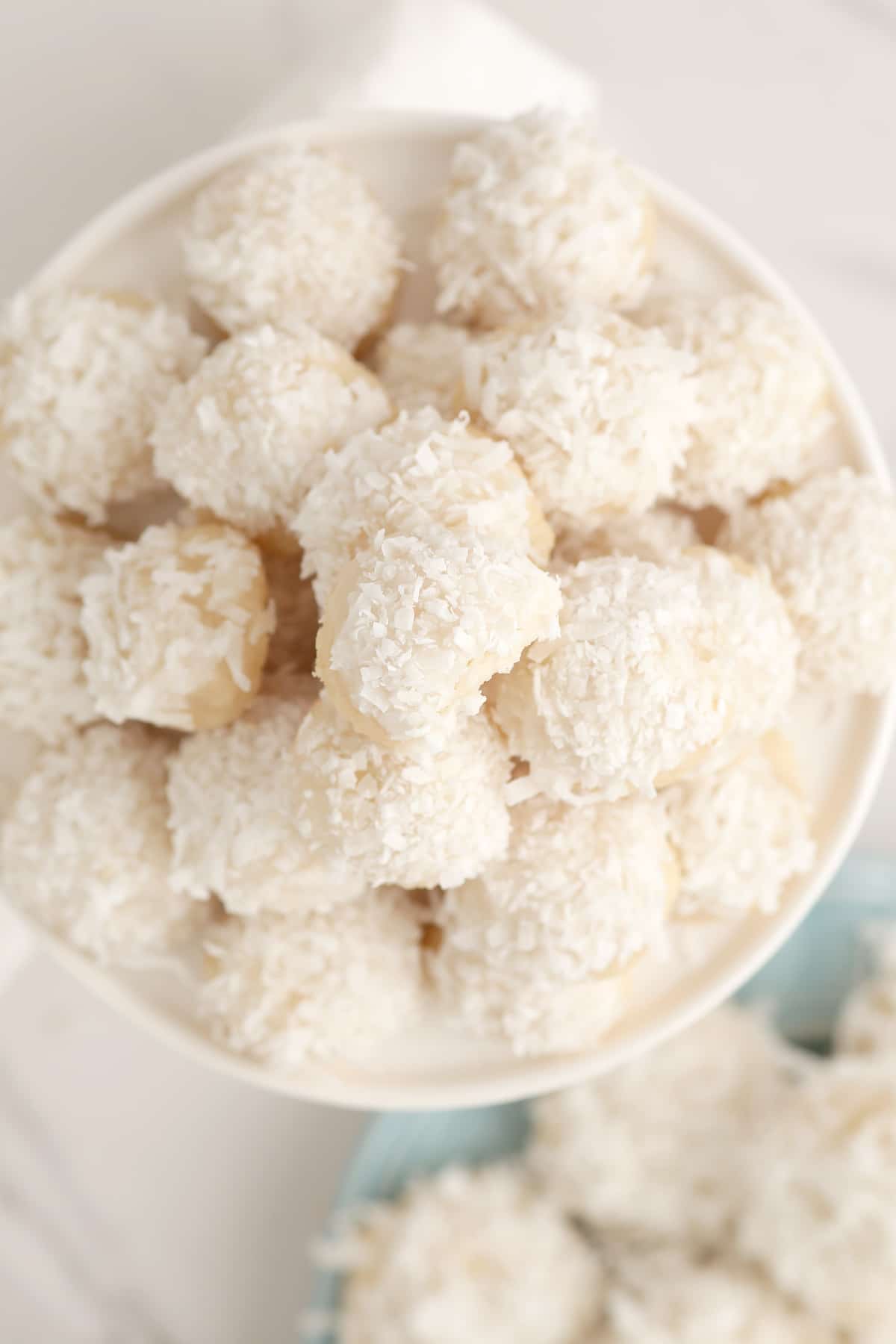 Coconut balls piled on a white serving plate. 
