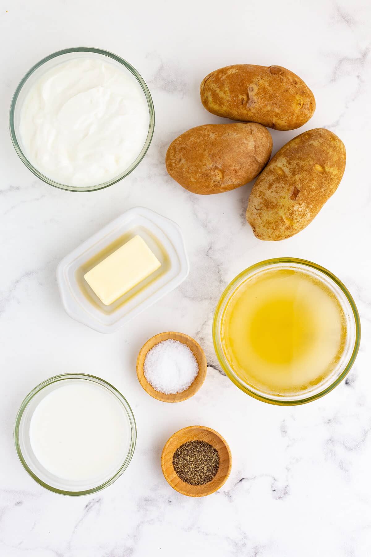 ingredients for crockpot mashed potatoes including russet potatoes, greek yogurt, butter, chicken broth, milk, salt, pepper