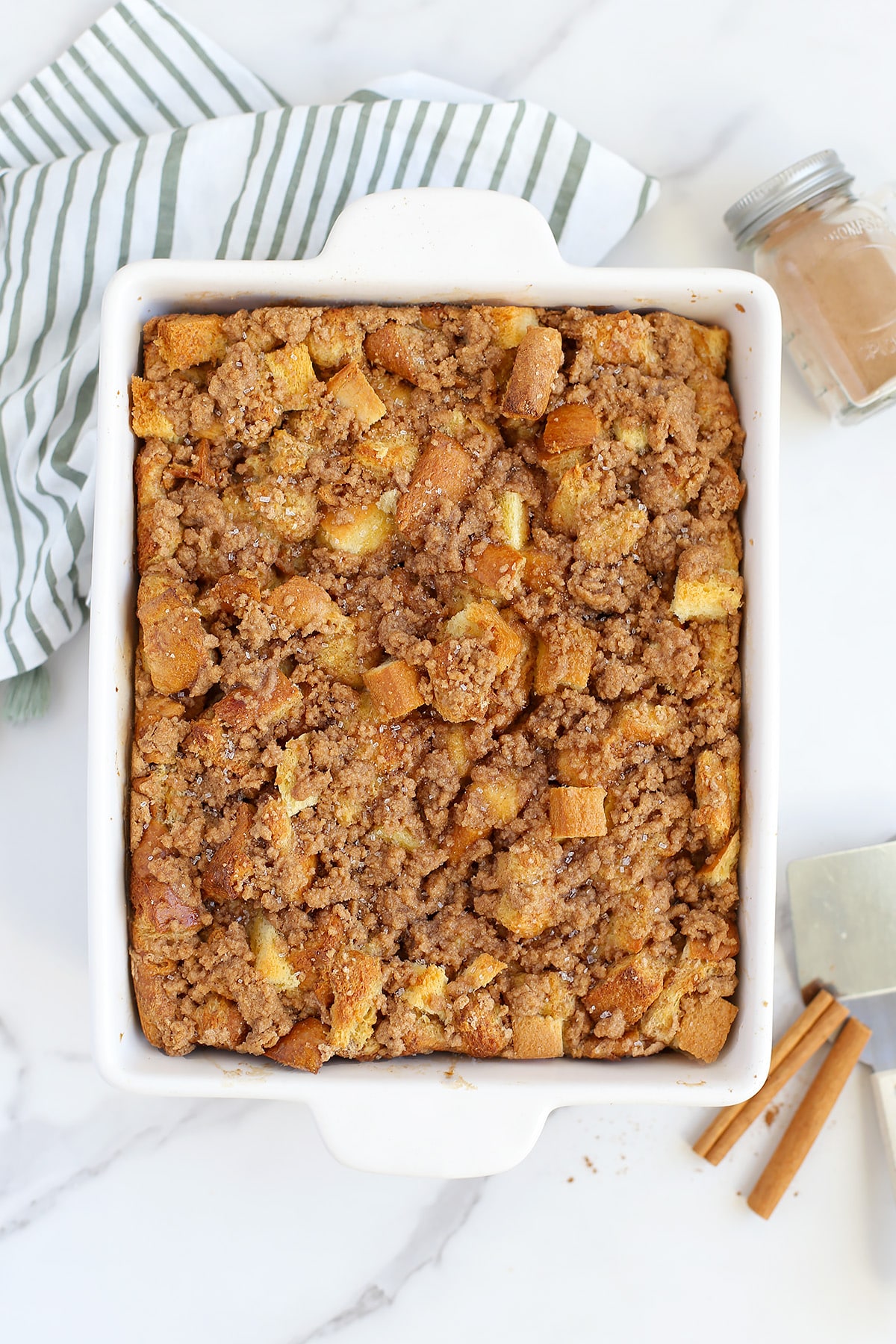 An overhead shot of french toast casserole topped with a cinnamon sugar streusel with a striped linen in the background. 