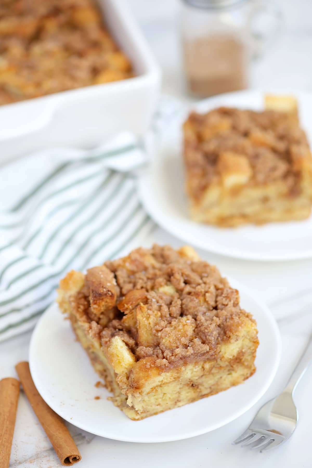 Slices of baked french toast on serving plates topped with a cinnamon sugar crumble. 
