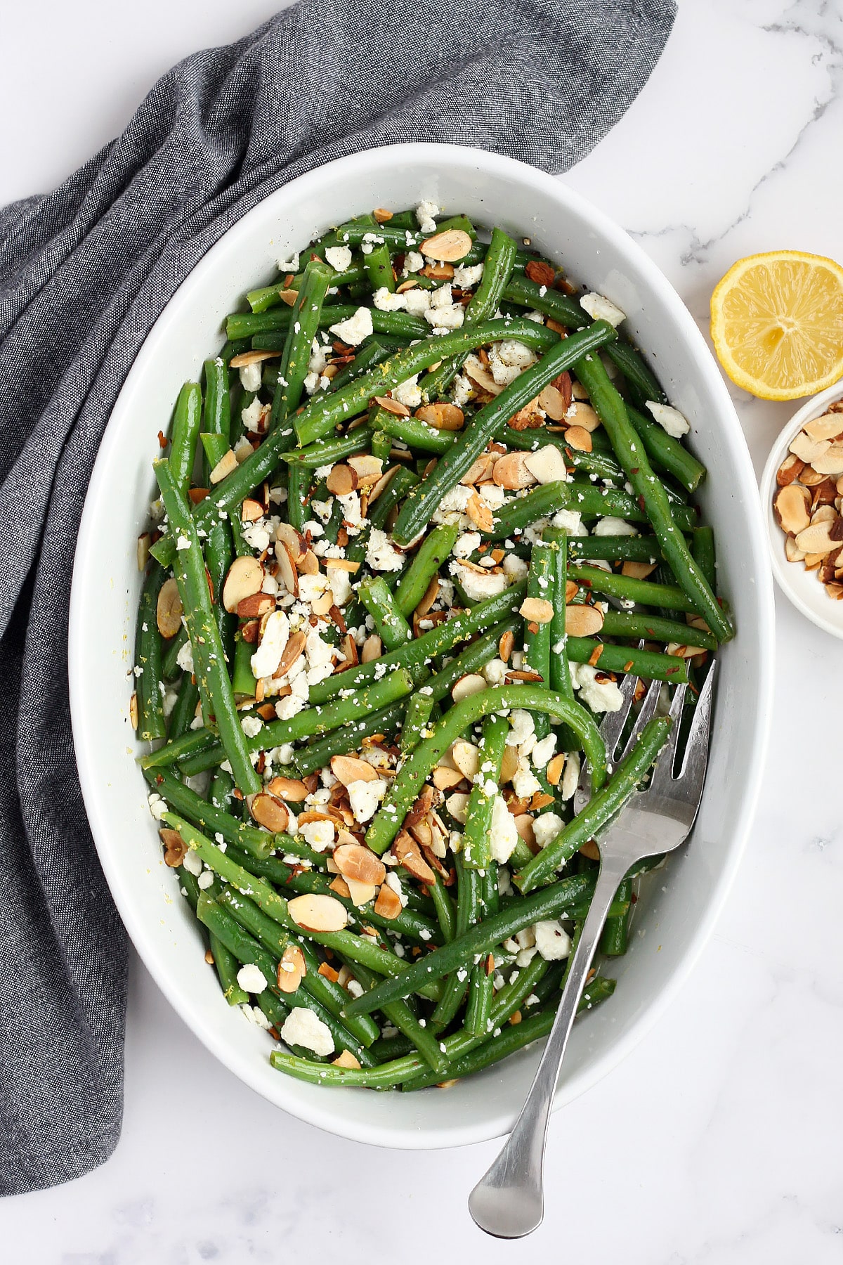 An overhead shot of green beans topped with toasted almonds and feta cheese. 
