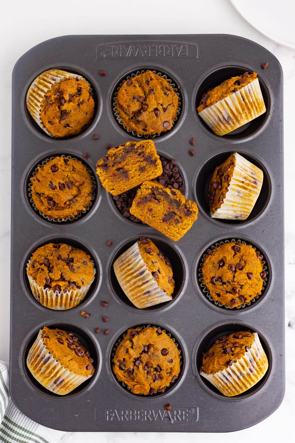 a muffin tin with chocolate chip pumpkin muffins