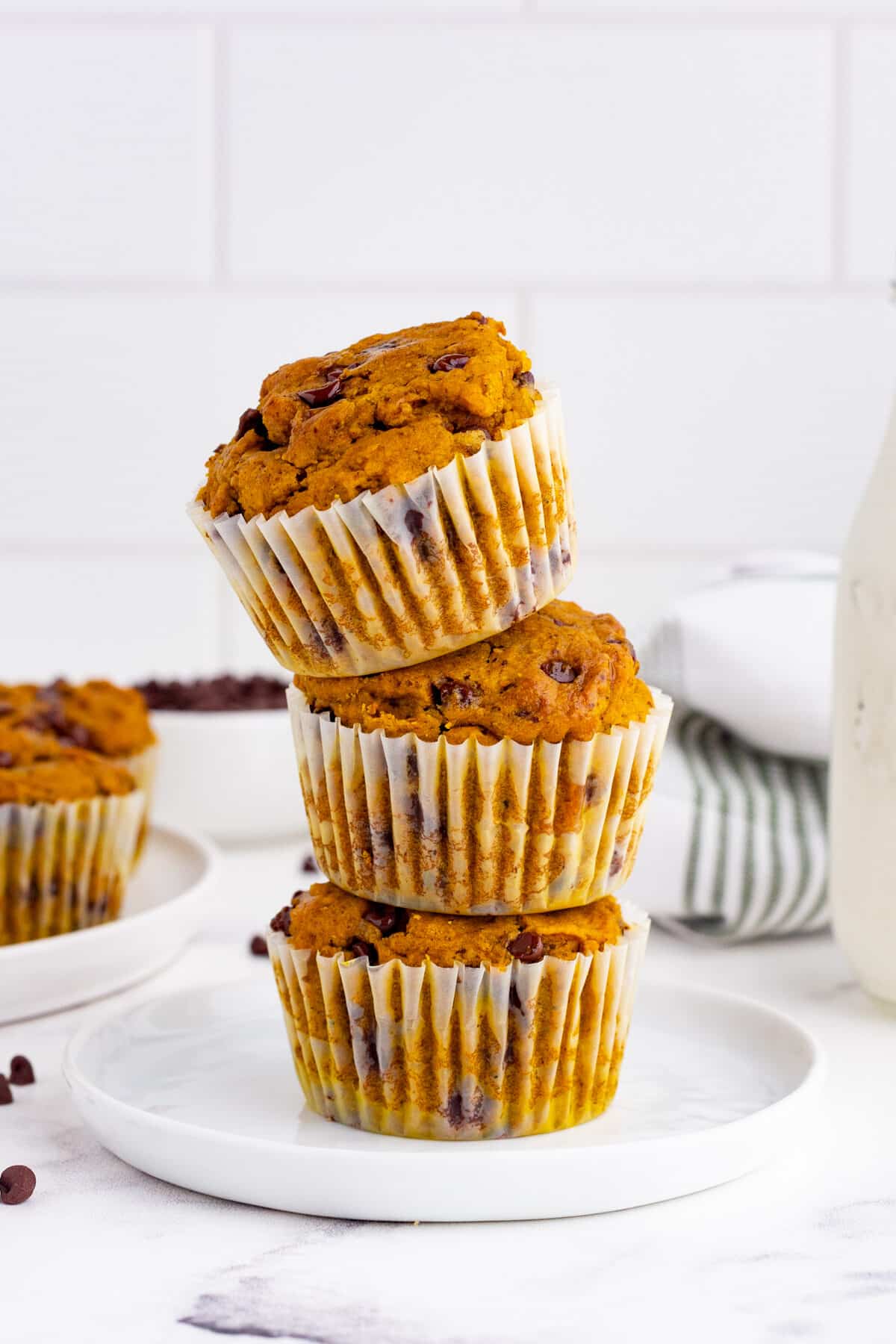 chocolate chip pumpkin muffins in a stack on a white countertop