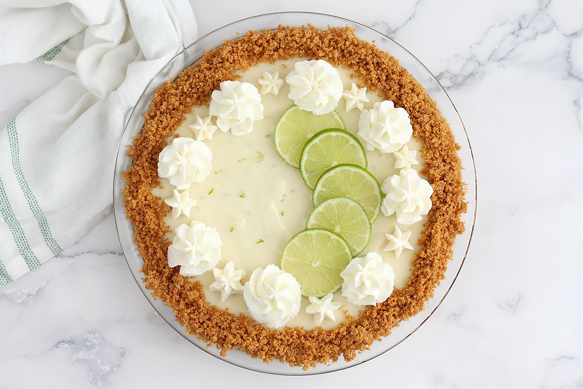 Key lime pie with a graham cracker crust topped with fresh limes and whipped cream. 