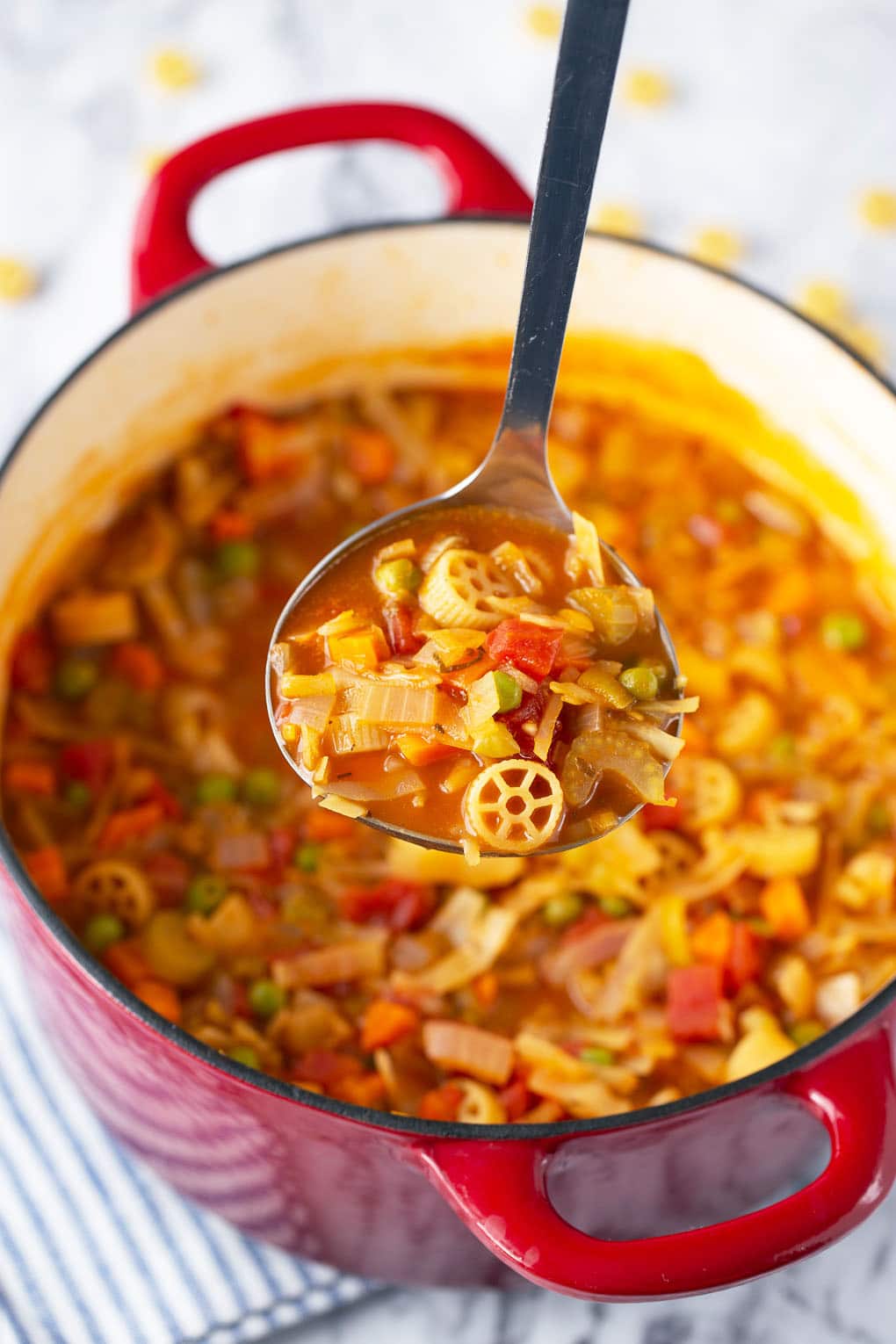 a ladle full of minestrone soup with the pot underneath