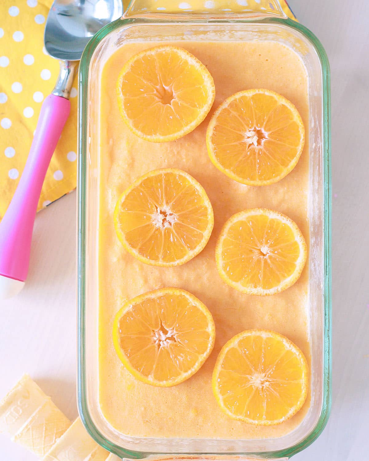 homemade orange creamsicle ice cream in a glass dish topped with fresh orange slices with a scoop