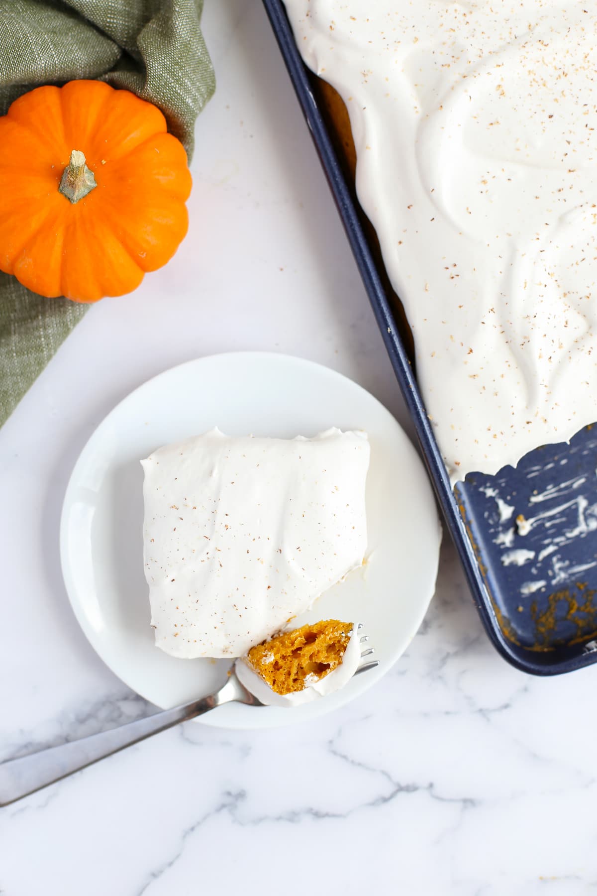 A slice of pumpkin cake with a whipped topping sprinkled with cinnamon. 