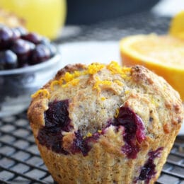 whole wheat orange blueberry muffin with blueberries and an orange in the background