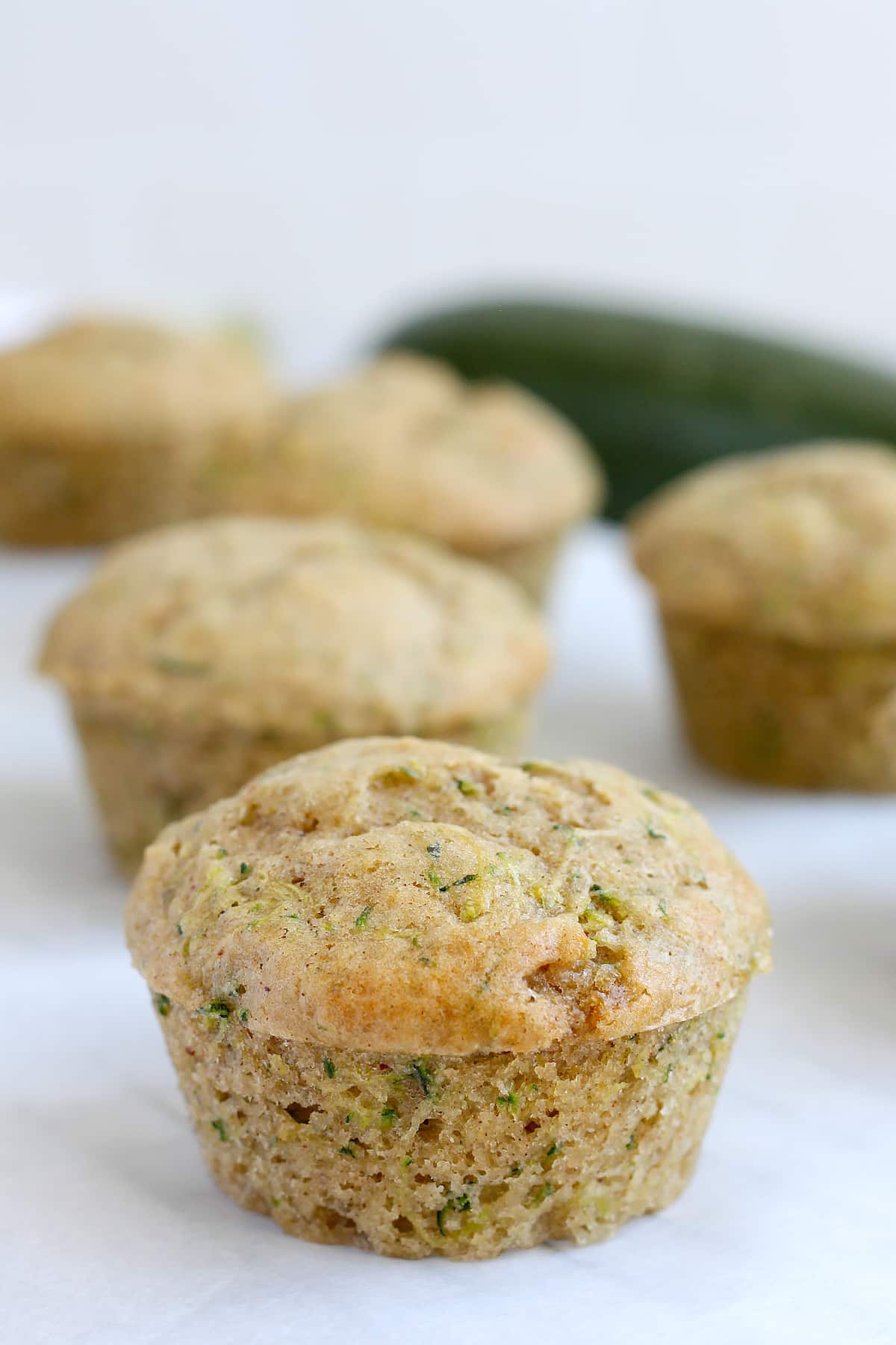 A zucchini muffin with a golden brown top, on a sheet of parchment paper. 
